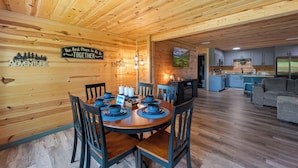 Un interno in legno con un tavolo da pranzo per quattro persone, un angolo cottura e un soggiorno.