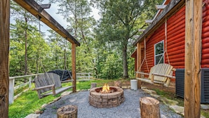 Una baita rustica con un focolare, un pontile in legno e poltrone Adirondack.