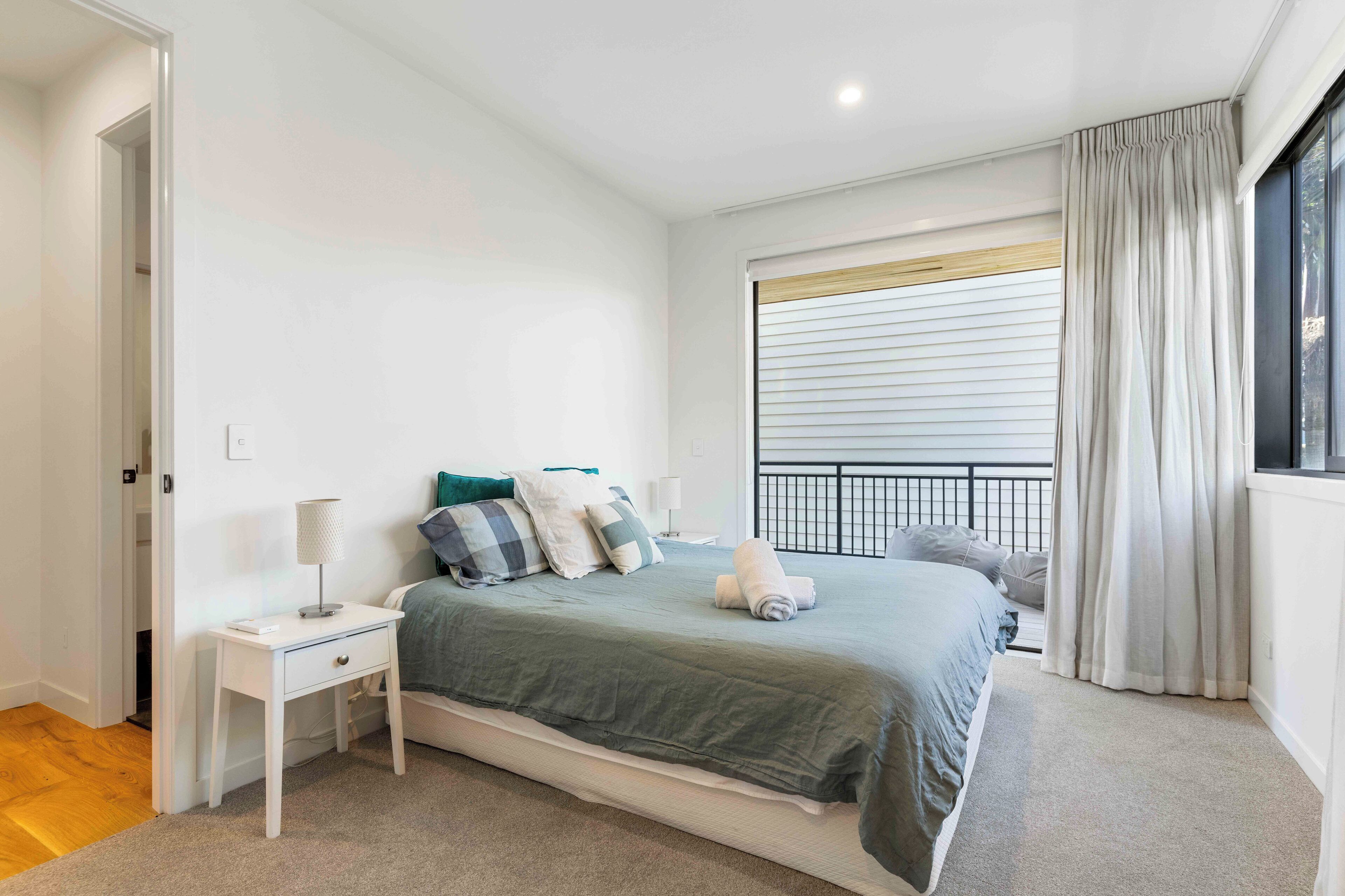 Une chambre à coucher avec un lit, une table de chevet et une fenêtre avec des rideaux.