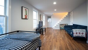 Een ruime kamer met een bed, een televisie, een bank en een trap naar een ander niveau.