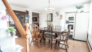 Een eetgedeelte met een houten tafel en stoelen, een kroonluchter en een keuken op de achtergrond.