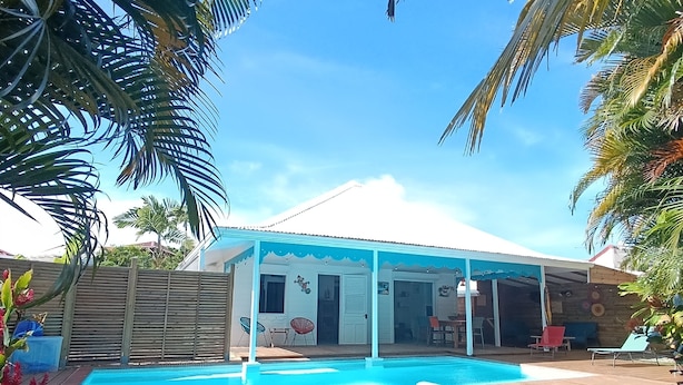 Un patio trasero con piscina, un porche cubierto y una terraza de madera.