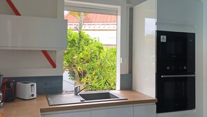 Una cocina moderna con horno integrado, un lavamanos y ventana con vista a un jardín.