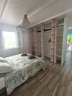 Quarto com cama, guarda-roupa e janela.