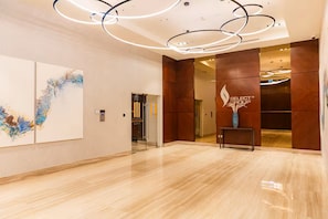 Una hall moderna con pavimento in marmo, opere d'arte astratte al muro, una reception e un logo sulla parete.