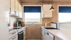 A modern kitchen with wooden cabinets, a built-in oven, a sink, and pendant lighting.