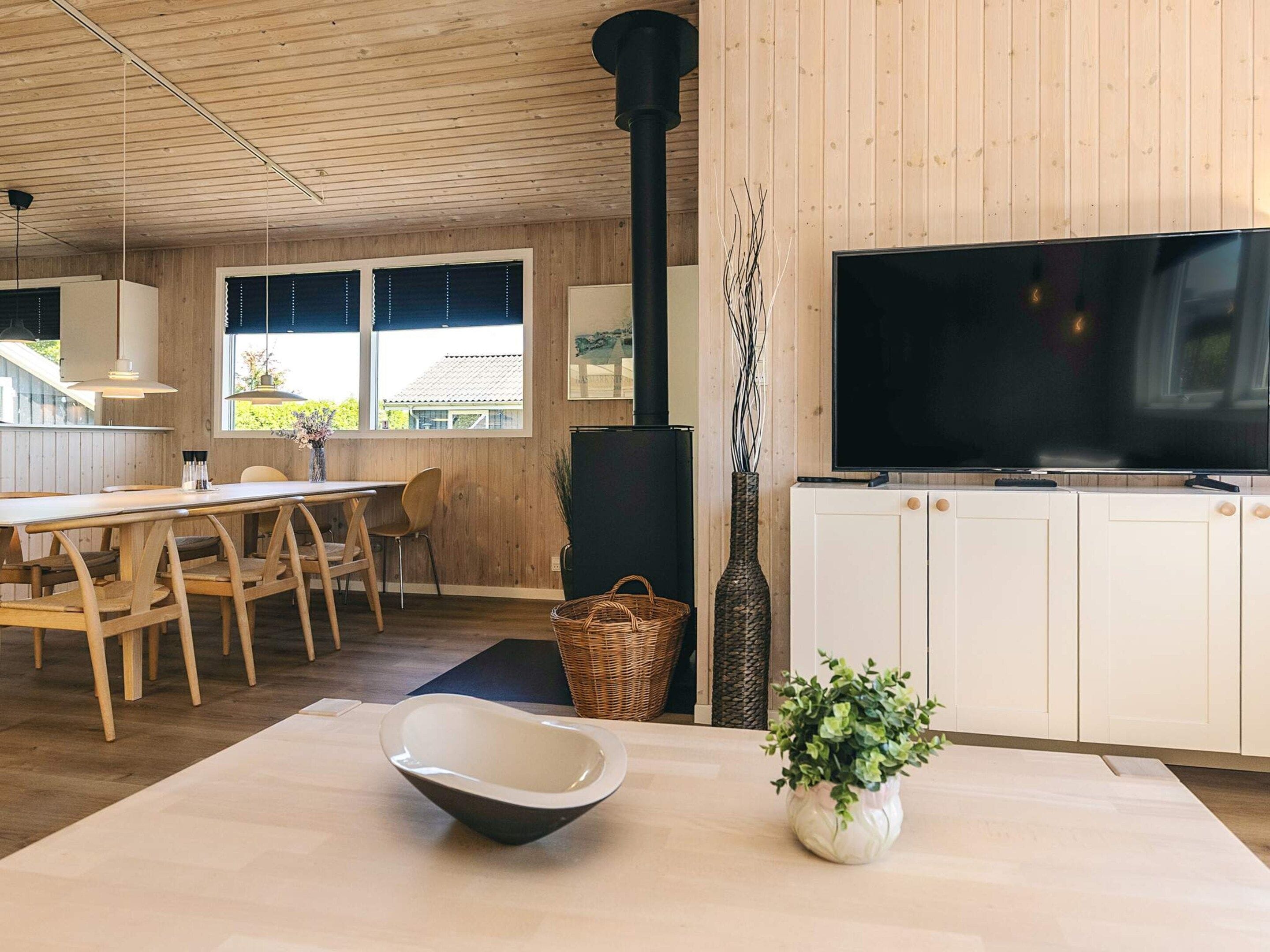 A modern kitchen with a large TV, wooden cabinets, and a dining area with a table and chairs.