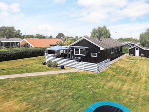 A black mobile home with a fenced deck, a small attached garage, and a well-maintained lawn.