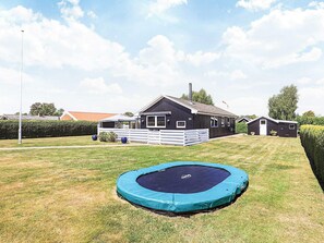 Propiedad residencial con casa, patio cercado y un trampolín.