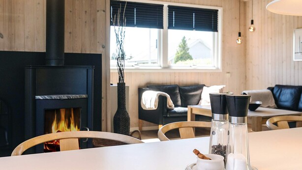 A cozy living room with a fireplace, wooden walls, a sofa, and a dining area with a table and chairs.