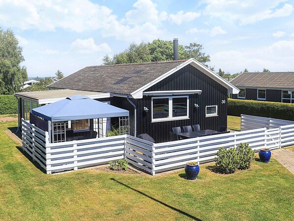 A black cabin with a white fence, a covered patio, and a number '36' on the side.