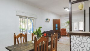 A dining area with a wooden table and chairs, a sofa, a patterned armchair, and a stone wall. - Cubo's Finca La Parra / private pool / BBQ / free Wi-Fi (Pizarra)