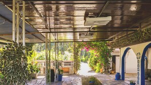 A covered patio area with a tiled floor, a wooden table, and potted plants. - Cubo's Finca La Parra / private pool / BBQ / free Wi-Fi (Pizarra)