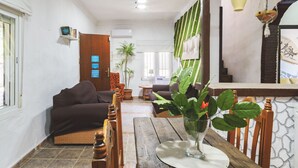 A living room with a sofa, a wooden table with a vase of flowers, and a green wall with a fan. - Cubo's Finca La Parra / private pool / BBQ / free Wi-Fi (Pizarra)