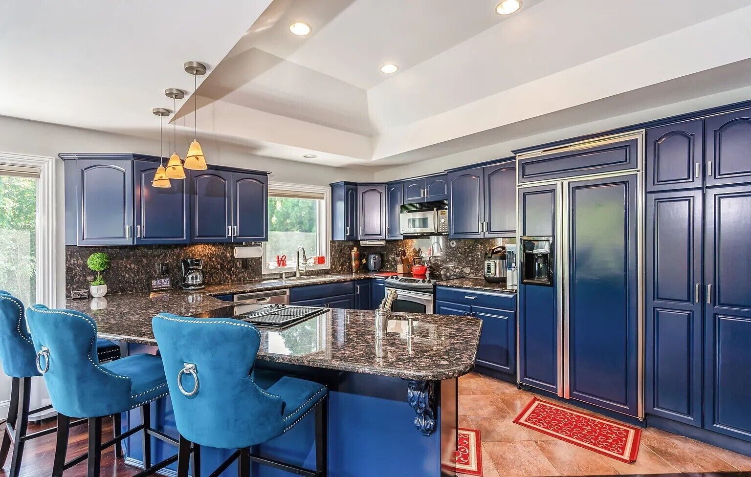Une cuisine moderne avec des meubles de couleur bleu foncé, un plan de travail en granit et un îlot central doté de tabourets de bar.