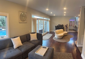 Een moderne woonkamer met een grijze modulaire bank, een passende voetenbankje, en een afstandsbediening op het bankje.