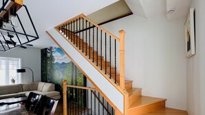 Un escalier avec des marches en bois et des balustrades noires, menant à l’étage supérieur.