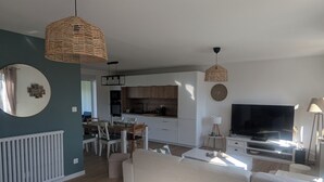 A modern living room with a sofa, a dining table, and a kitchen area in the background.