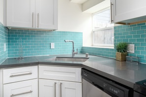 Enjoy cooking in this well-equipped kitchen with a stainless steel sink, dishwasher, and vibrant tile backsplash.