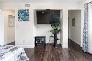 Relax in a serene space with a large bed, flat-screen TV, and a touch of greenery.