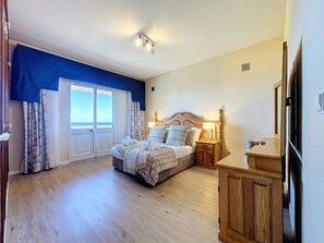 A bedroom with a large bed, a nightstand, a wooden cabinet, and a view through a door. - Villa Mar by Atlantic Holiday (Porto Moniz)