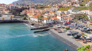 A coastal town with terraced houses, a marina with boats, and a rocky breakwater.