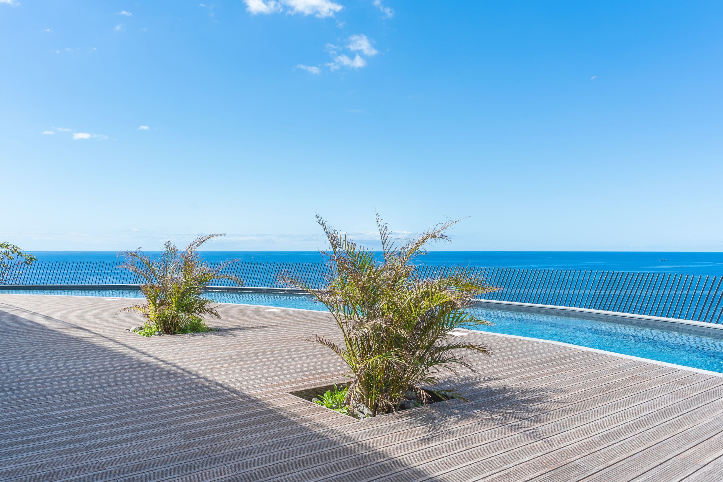A wooden deck with a pool and a view of the ocean.