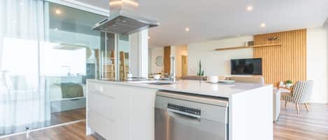 A modern kitchen with a central island, stainless steel appliances, and a large window.