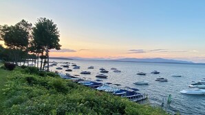 A marina with boats docked along the shore, surrounded by greenery and trees. - Winnipesaukee Condo Walk to Beach, Pool, Near Gunstock (Gilford)