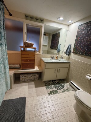 Un baño con lavamanos, espejo e inodoro.