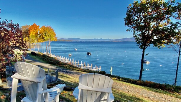 Two Adirondack chairs facing a lake with boats and a dock. - Winnipesaukee Condo Walk to Beach, Pool, Near Gunstock (Gilford)