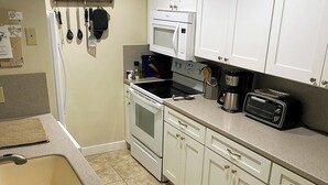 A kitchen with white cabinets, a microwave, a toaster, and a sink. - Winnipesaukee Condo Walk to Beach, Pool, Near Gunstock (Gilford)