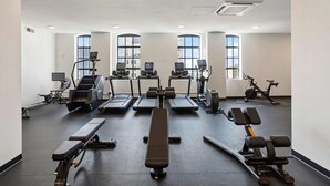 A gym with treadmills, elliptical machines, a bench, and dumbbells. - Optimum - Downtown Oasis! (Birmingham)