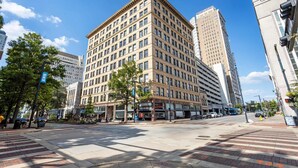 A multi-story hotel with a classic architectural design, featuring a prominent corner location with a large entrance and visible signage for businesses on the ground floor. - Optimum - Downtown Oasis! (Birmingham)