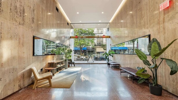 A spacious lobby with a polished marble floor, a wooden bench, a potted plant, and a glass wall offering a view of the outside. - Optimum - Downtown Oasis! (Birmingham)