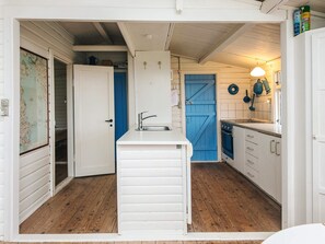 A compact kitchen with a white countertop, a blue door, and wooden flooring. - 6 Person Holiday Home in Haderslev (Haderslev)