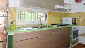 A kitchen with a green countertop, stainless steel sink, wooden cabinets, a microwave, and an oven.