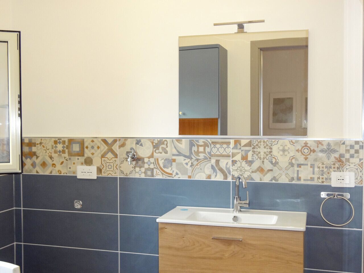 A bathroom with a sink, mirror, and patterned tiles.