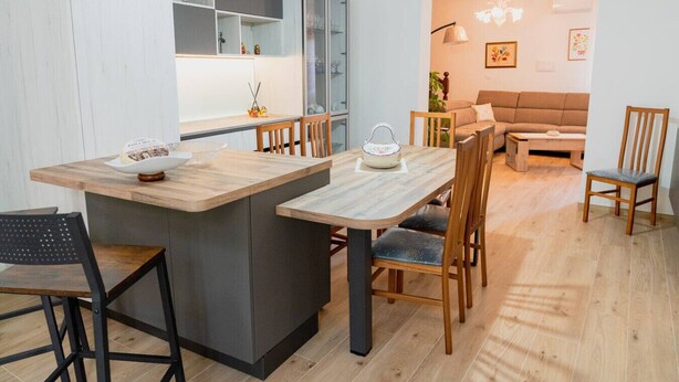 Una cocina moderna con una isla central, sillas de madera y una mesa de comedor.
