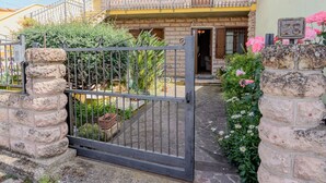 Edificio residencial con un portón de piedra, un balcón con macetas y un cartel con el número de la dirección.