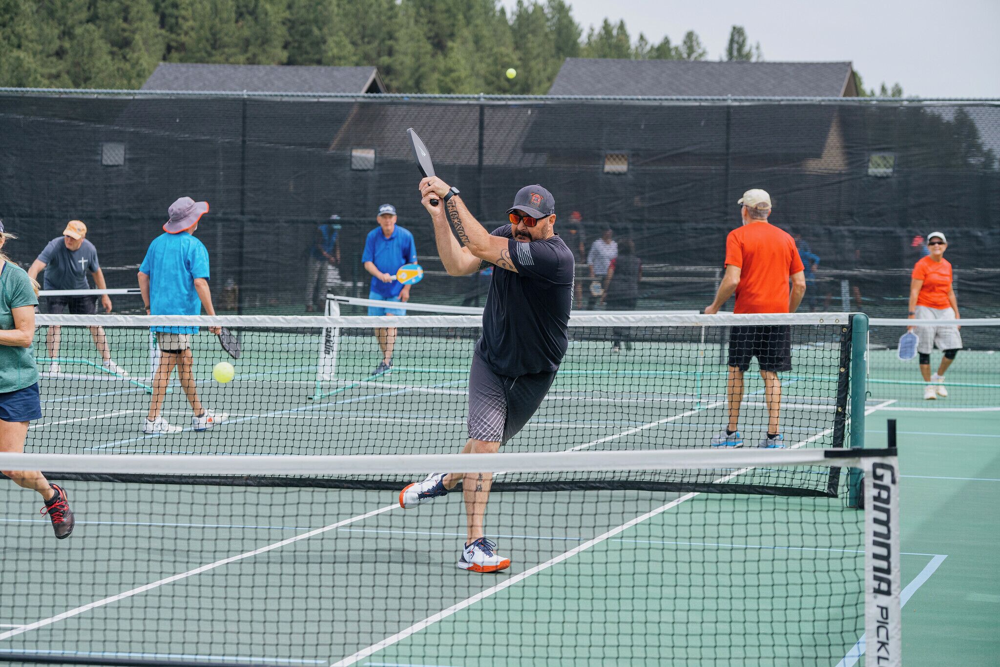Una cancha de tenis con red, jugadores y espectadores.