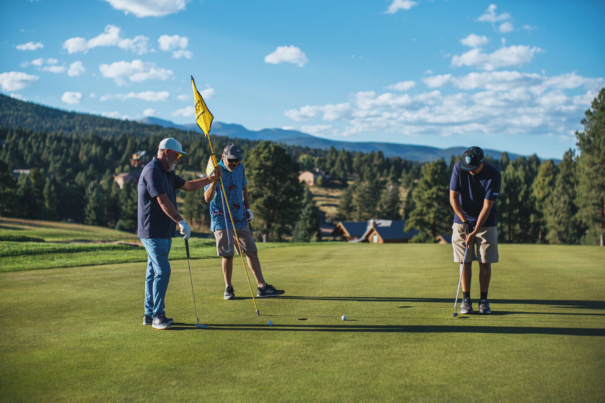 Un campo de golf con jugadores y un marcador de bandera.
