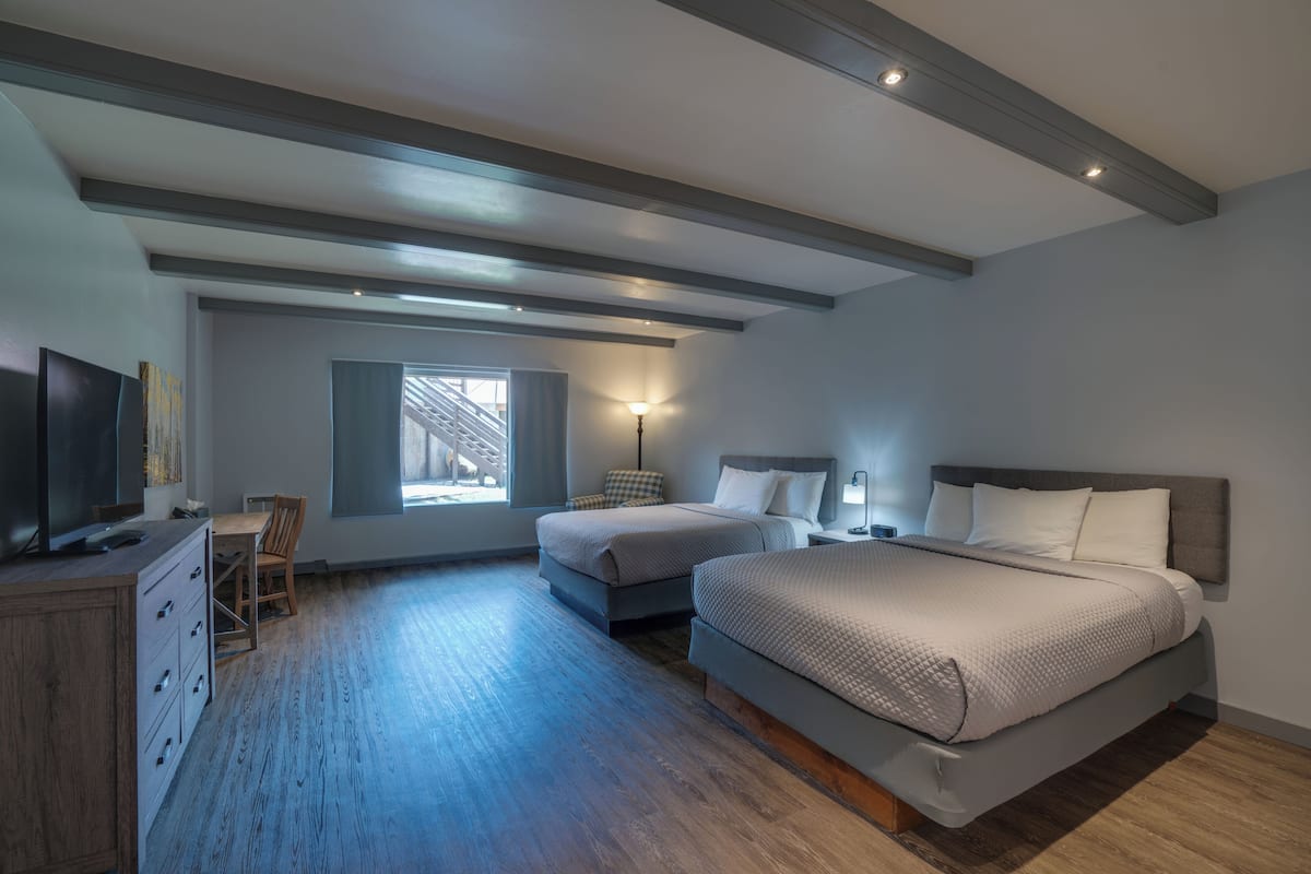 A bedroom with two beds, a desk, and a chair.