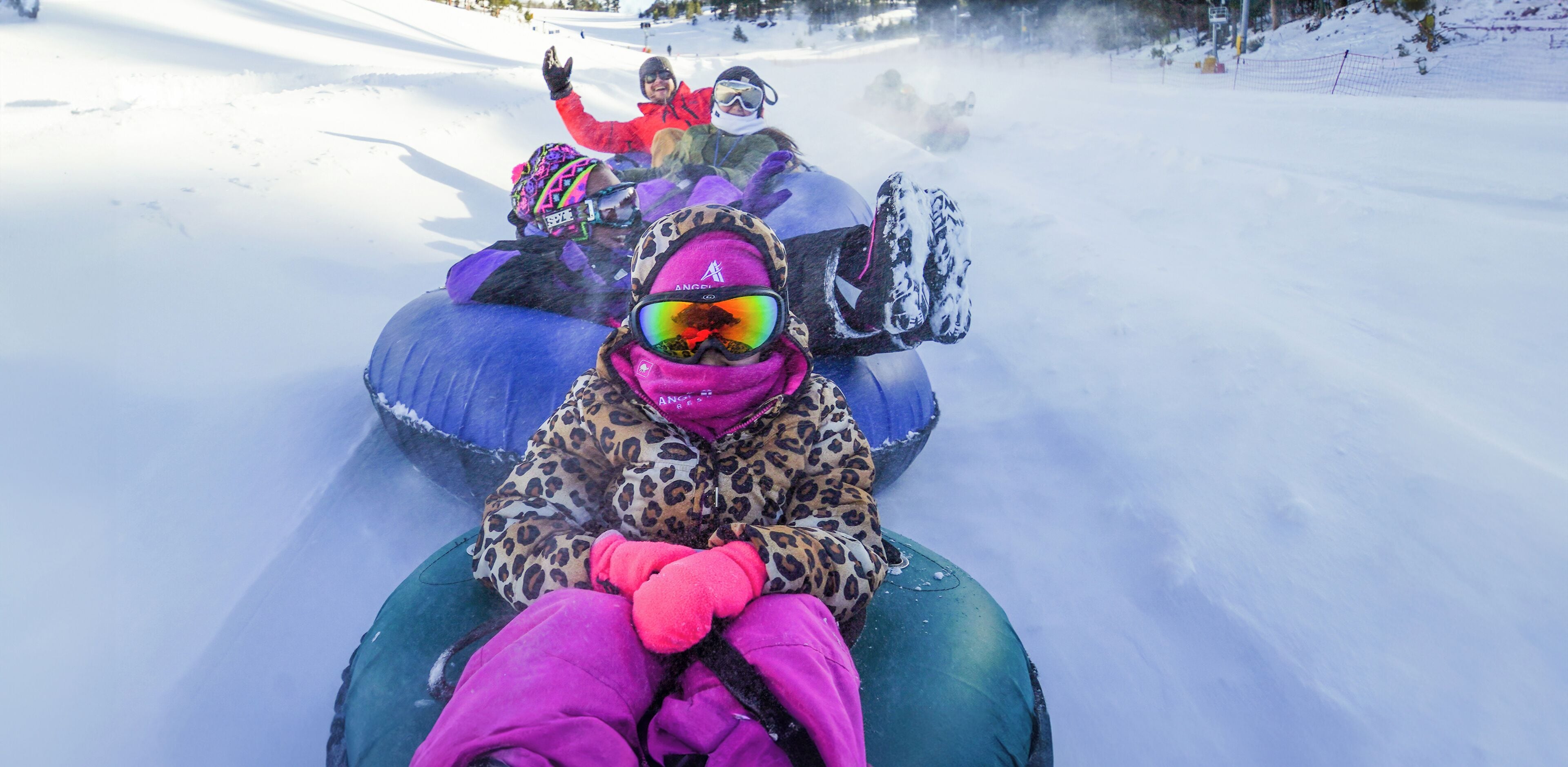 A snow-covered slope with people on snow tubes.