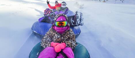 A snow-covered slope with people on snow tubes.