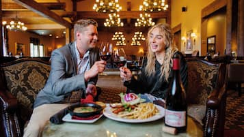 Una pareja sentada a una mesa con una botella de vino, platos de comida y una vela.