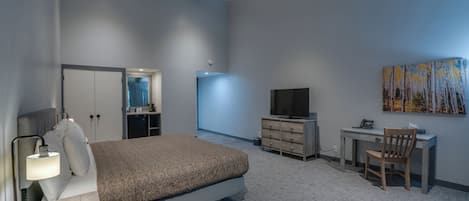 Un dormitorio moderno con cama, escritorio, televisión y obras de arte.