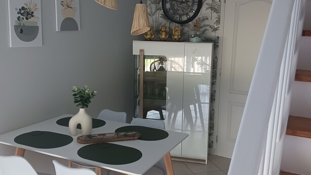 Ruokailutila, jossa on valkoinen pöytä, neljä tuolia ja katosta roikkuvat riippuvalaisimet.