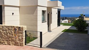 A modern building with a stone wall and a metal gate.
