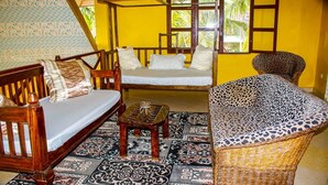 Una habitación con un sofá de madera, un tapete estampado y una silla de mimbre.